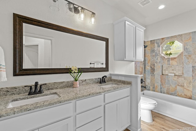 full bathroom featuring hardwood / wood-style floors, vanity, toilet, and tiled shower / bath