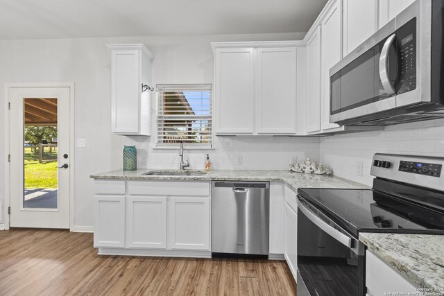 kitchen featuring sink, tasteful backsplash, light hardwood / wood-style floors, white cabinets, and appliances with stainless steel finishes