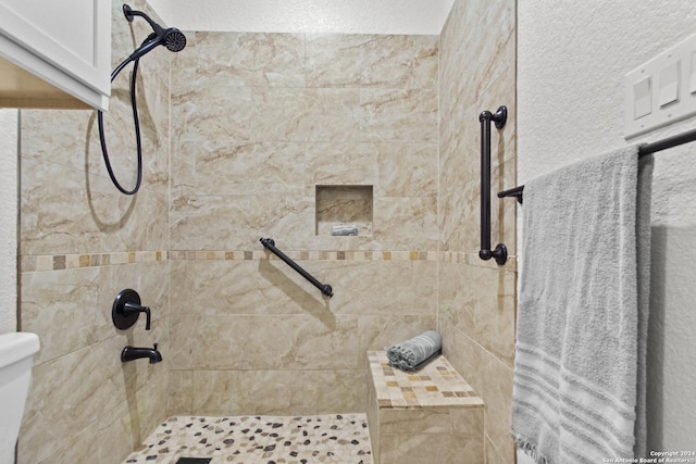 bathroom featuring tiled shower and toilet