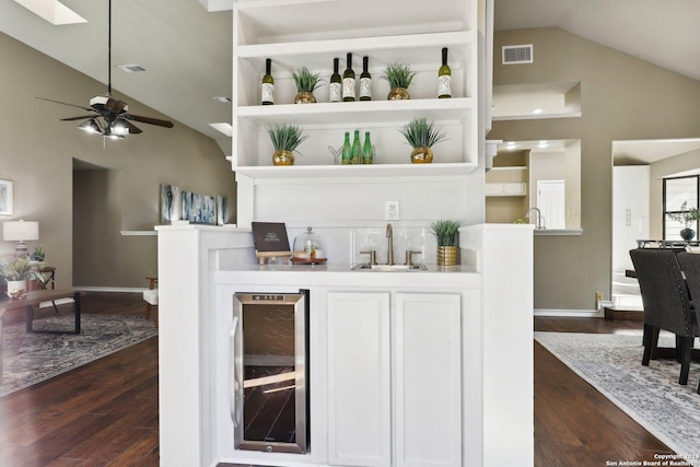 bar featuring ceiling fan, sink, beverage cooler, dark hardwood / wood-style floors, and vaulted ceiling