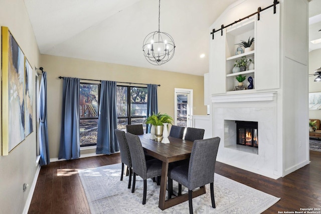 dining space featuring a barn door, built in features, dark wood-type flooring, and vaulted ceiling