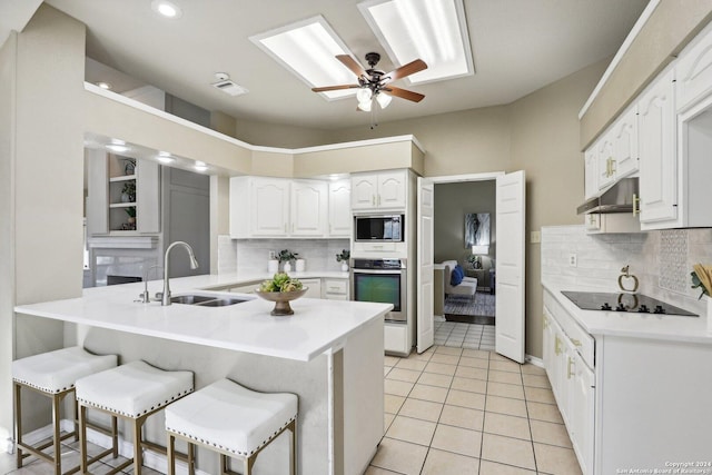 kitchen with a kitchen breakfast bar, sink, white cabinetry, kitchen peninsula, and stainless steel appliances