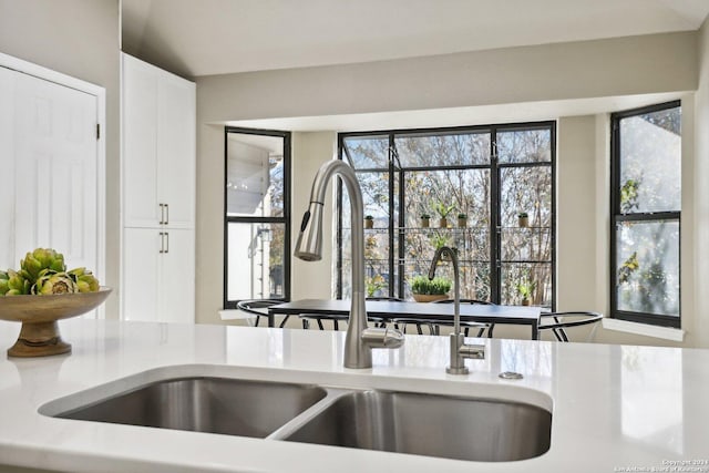 kitchen featuring white cabinets, lofted ceiling, a healthy amount of sunlight, and sink