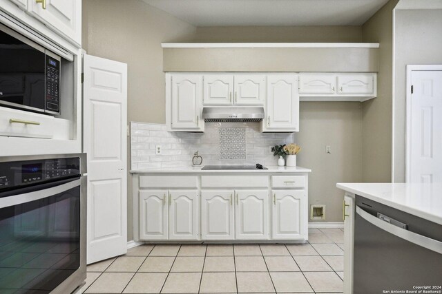 kitchen with white cabinets, light tile patterned floors, backsplash, and stainless steel appliances