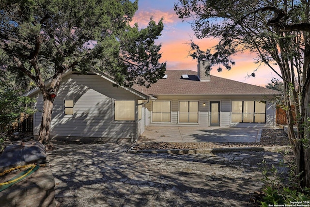 back house at dusk featuring a patio