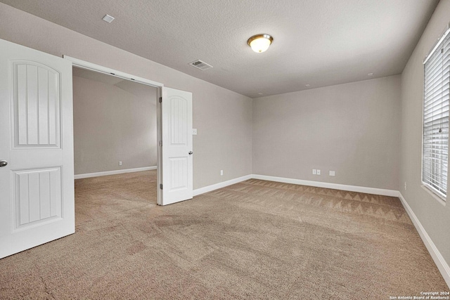 unfurnished room with a textured ceiling and carpet floors