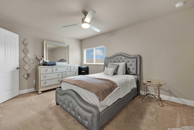 bedroom featuring ceiling fan, light colored carpet, and a textured ceiling