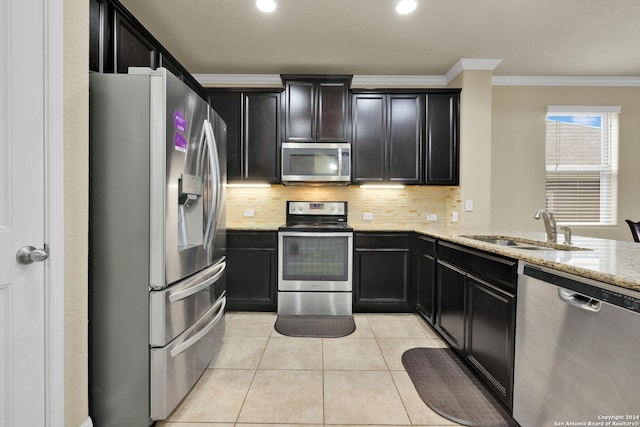 kitchen featuring appliances with stainless steel finishes, tasteful backsplash, light stone counters, ornamental molding, and sink