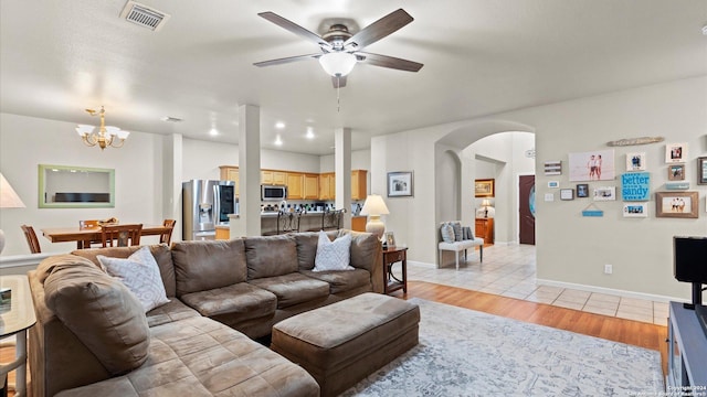 living room featuring light hardwood / wood-style flooring and ceiling fan with notable chandelier