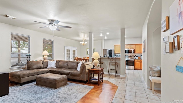 tiled living room featuring a textured ceiling and ceiling fan with notable chandelier