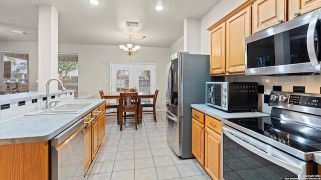 kitchen featuring sink, stainless steel appliances, backsplash, a chandelier, and light tile patterned floors