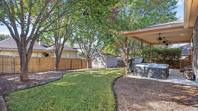 view of yard with ceiling fan, a shed, and a hot tub