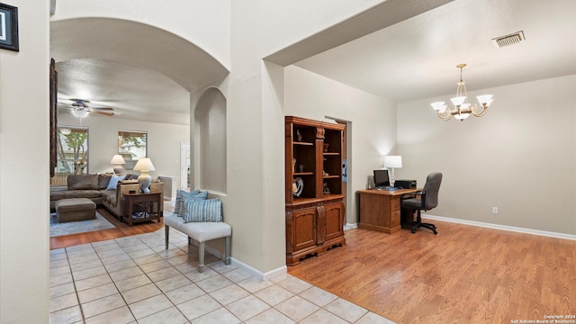 office featuring ceiling fan with notable chandelier and light wood-type flooring