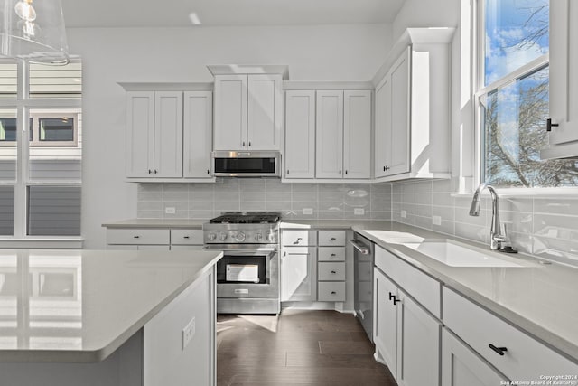 kitchen featuring sink, dark wood-type flooring, pendant lighting, white cabinets, and appliances with stainless steel finishes