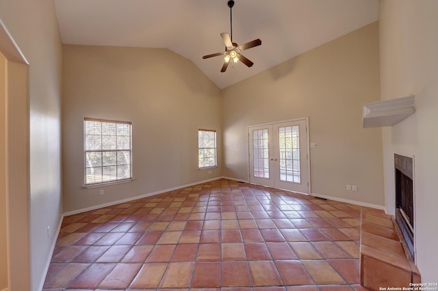 unfurnished living room with ceiling fan, french doors, high vaulted ceiling, and a healthy amount of sunlight