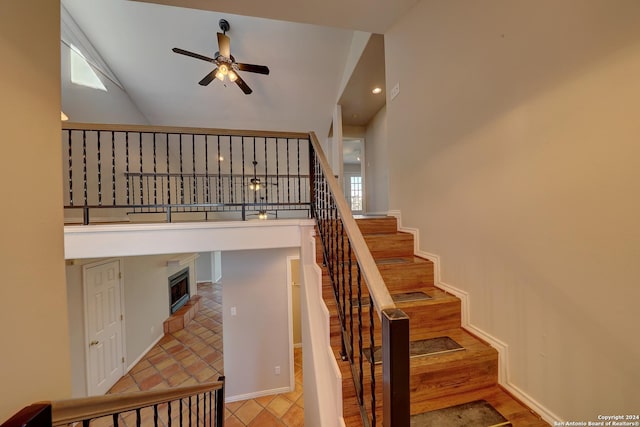 staircase featuring hardwood / wood-style flooring, ceiling fan, and a high ceiling