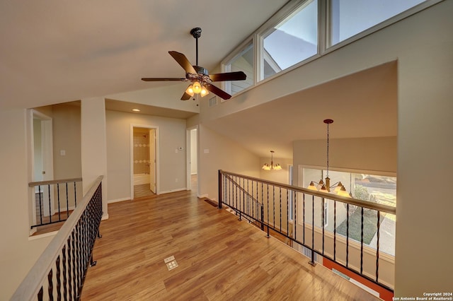 corridor featuring light hardwood / wood-style floors, high vaulted ceiling, and an inviting chandelier