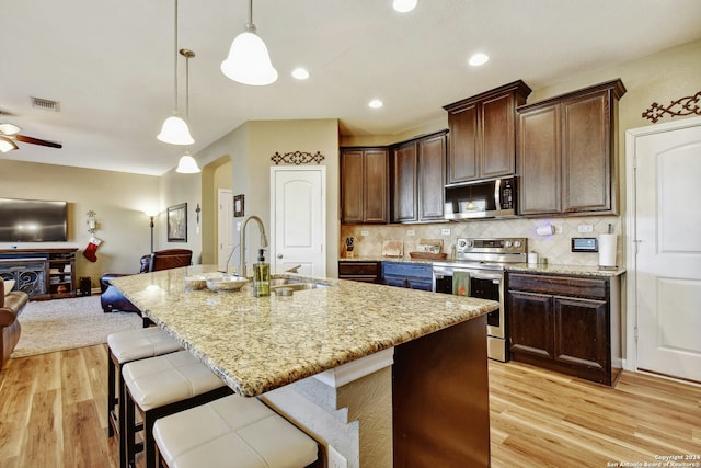 kitchen featuring light hardwood / wood-style floors, a kitchen island with sink, sink, and appliances with stainless steel finishes