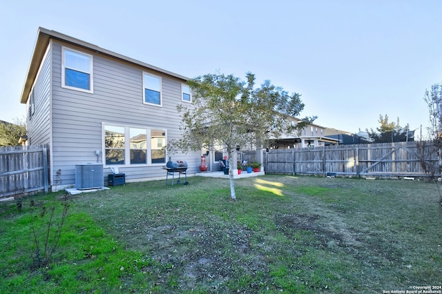 back of property with a lawn, central AC, and a patio