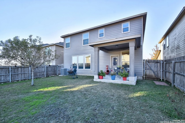 rear view of house featuring central air condition unit, a yard, and a patio