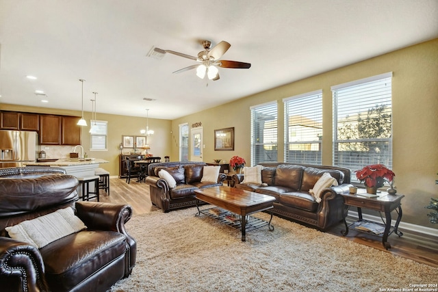 living room with hardwood / wood-style floors, ceiling fan with notable chandelier, and sink