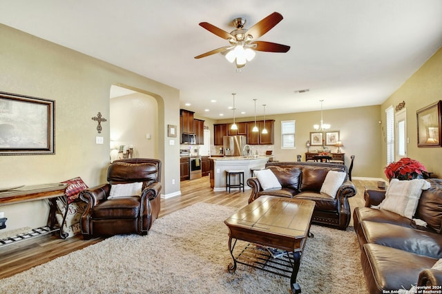 living room featuring ceiling fan with notable chandelier and light hardwood / wood-style floors