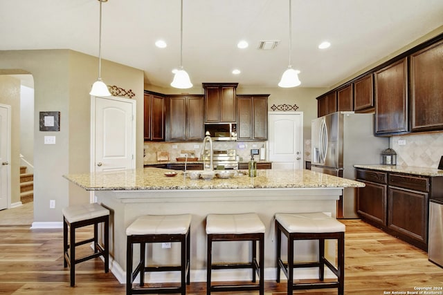 kitchen featuring light hardwood / wood-style floors, an island with sink, and appliances with stainless steel finishes