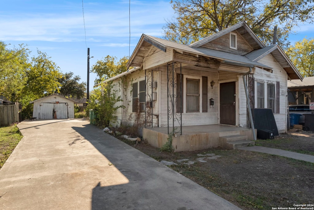 bungalow-style home with covered porch, a garage, and an outdoor structure