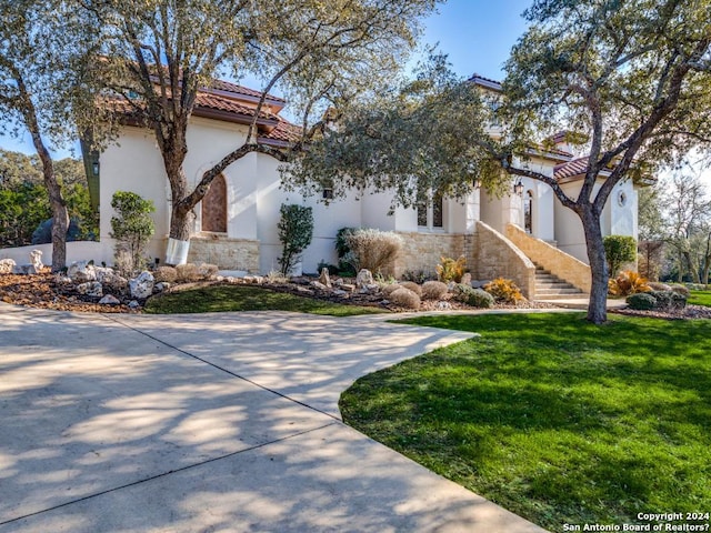 view of home's exterior featuring a tile roof, a yard, stucco siding, stairway, and stone siding