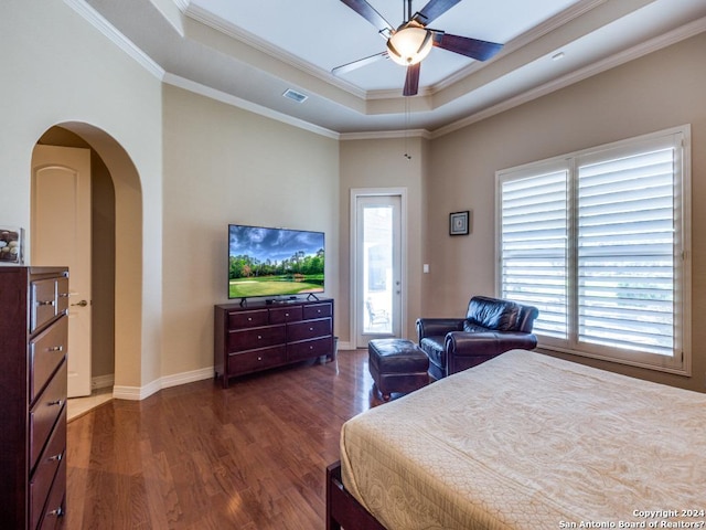 bedroom with access to exterior, a tray ceiling, arched walkways, dark wood finished floors, and ornamental molding