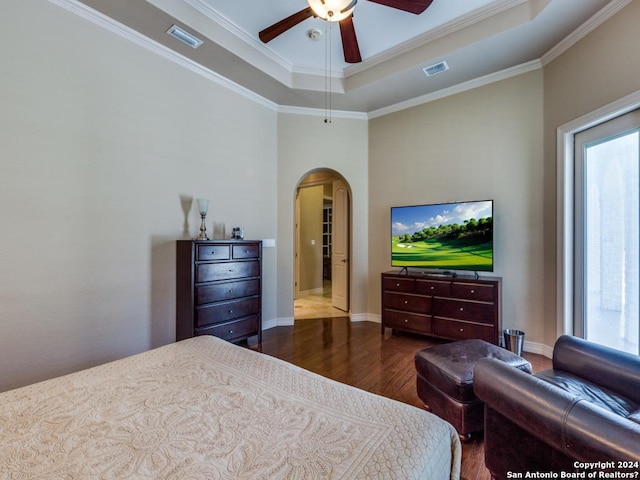 bedroom with arched walkways, wood finished floors, visible vents, a raised ceiling, and crown molding