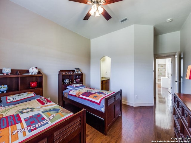 bedroom with arched walkways, dark wood-style flooring, visible vents, ceiling fan, and baseboards