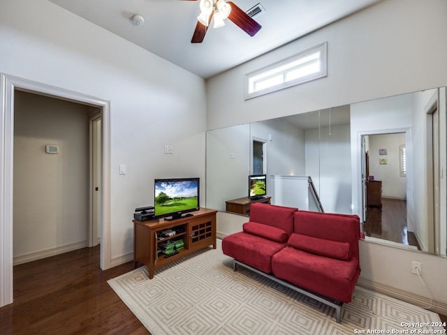 living room with baseboards, wood finished floors, visible vents, and a ceiling fan