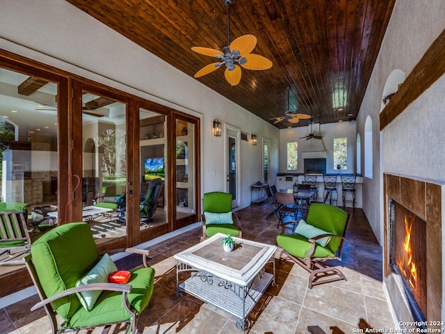 sunroom / solarium with wood ceiling, a lit fireplace, arched walkways, and a ceiling fan