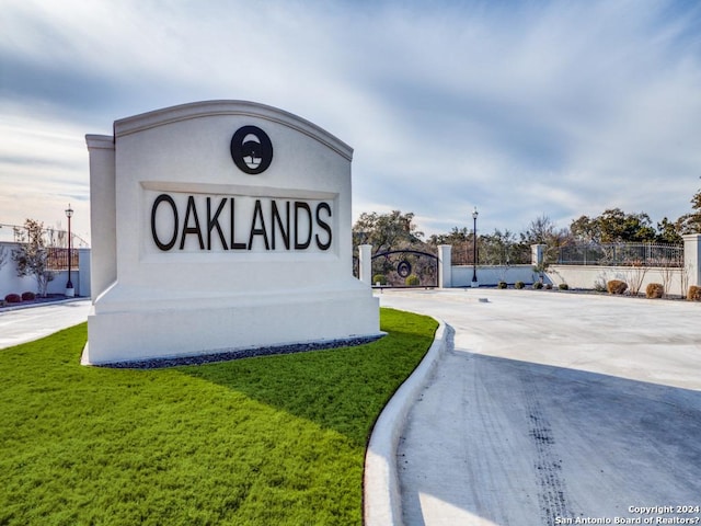 community / neighborhood sign featuring fence and a yard