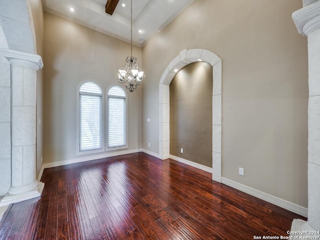 empty room with ornate columns, wood-type flooring, baseboards, and beamed ceiling