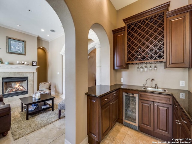 bar with visible vents, a tile fireplace, wine cooler, wet bar, and a sink