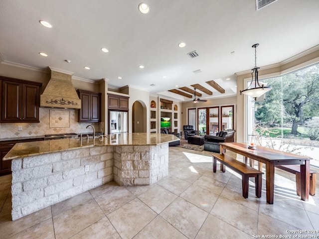 kitchen with arched walkways, a spacious island, appliances with stainless steel finishes, open floor plan, and premium range hood