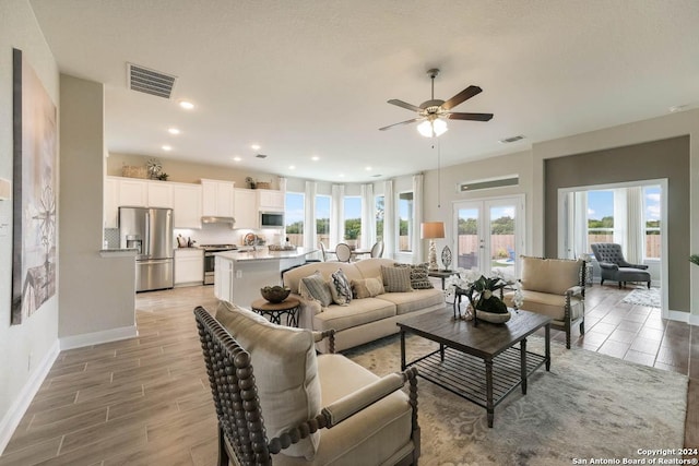 living room with sink, french doors, ceiling fan, and light wood-type flooring