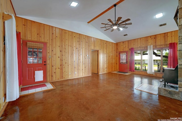 unfurnished living room with ceiling fan, concrete floors, wooden walls, and vaulted ceiling