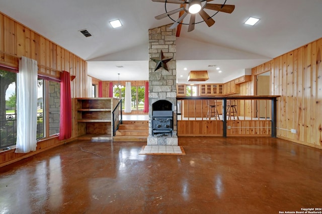 unfurnished living room featuring wooden walls, plenty of natural light, and vaulted ceiling