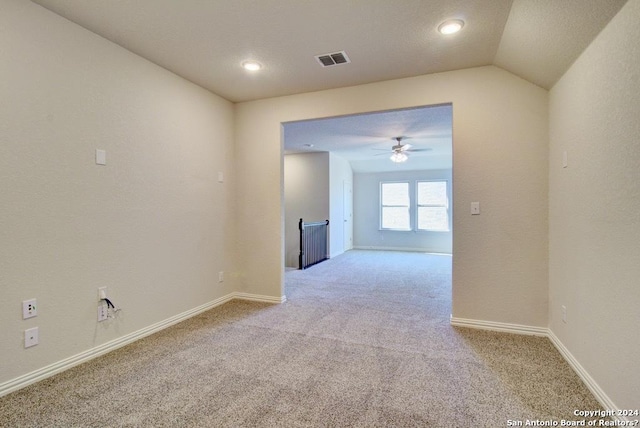 carpeted spare room with vaulted ceiling