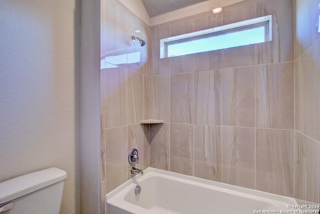 bathroom featuring toilet and tiled shower / bath