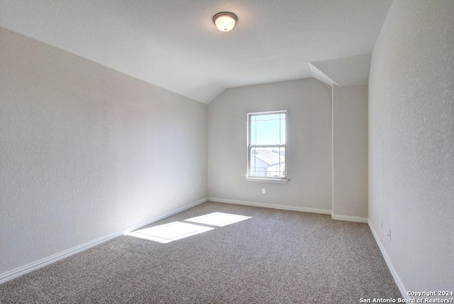 carpeted spare room featuring vaulted ceiling