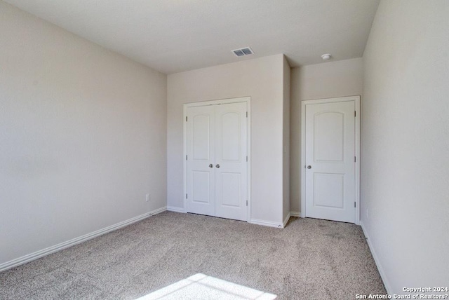 unfurnished bedroom featuring light carpet and a closet