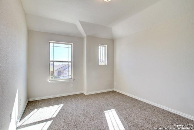 carpeted spare room featuring vaulted ceiling