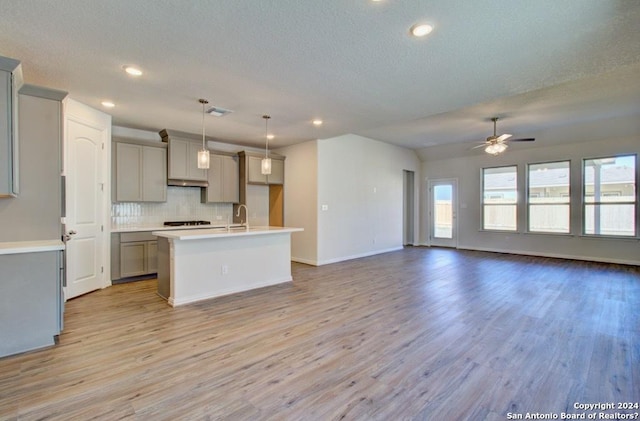 kitchen featuring pendant lighting, a center island with sink, ceiling fan, gray cabinets, and light hardwood / wood-style floors