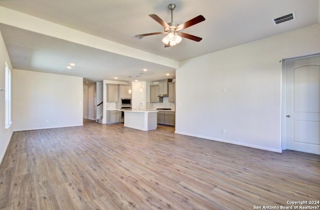 unfurnished living room with ceiling fan, sink, and wood-type flooring