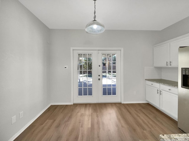 unfurnished dining area featuring light wood-type flooring and french doors