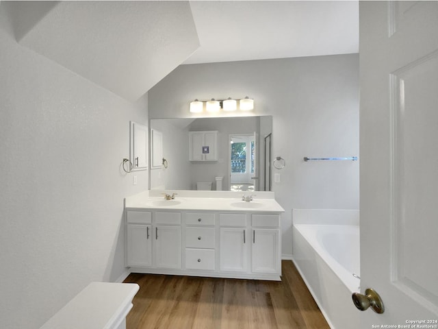 bathroom featuring vanity, hardwood / wood-style flooring, vaulted ceiling, and a bathing tub